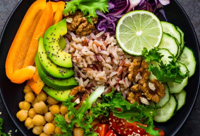bowl of chickpeas, vegetables, rice, avocado, and nuts