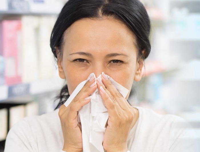 woman wiping nose with tissue