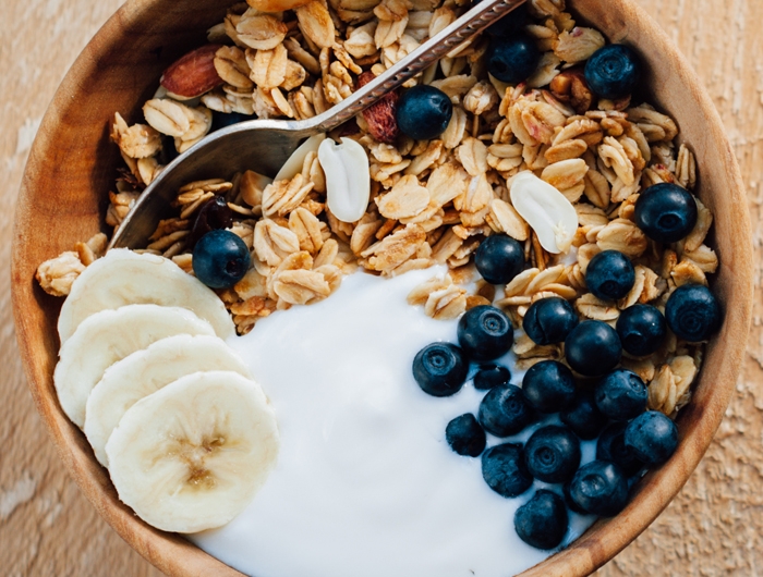 a bowl of oatmeal granola with peanuts blueberry and banana