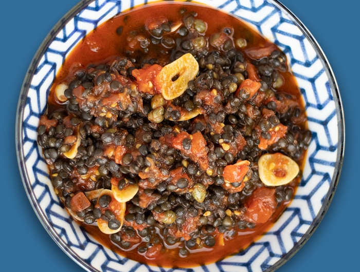 tomato and black lentil dish on blue and white plate
