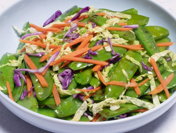 Plate with stir-fried snow peas, shredded carrots and cabbage