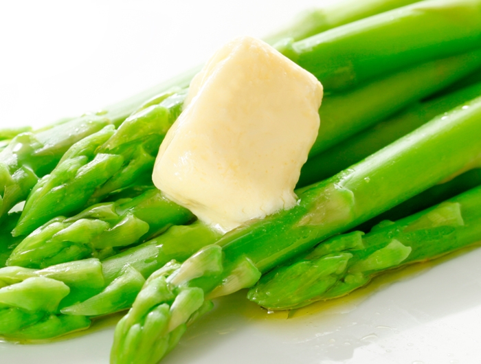 green asparagus stalks with melting pat of butter 