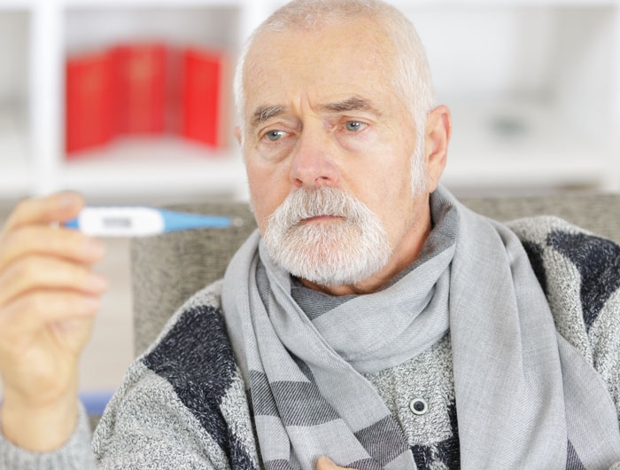 older man in scarf looking at thermometer