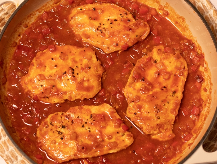 large pot with 4 chicken breasts in red sauce
