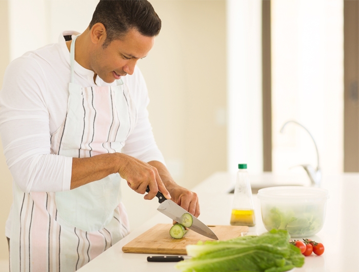man chopping vegetables in bright kitchen
