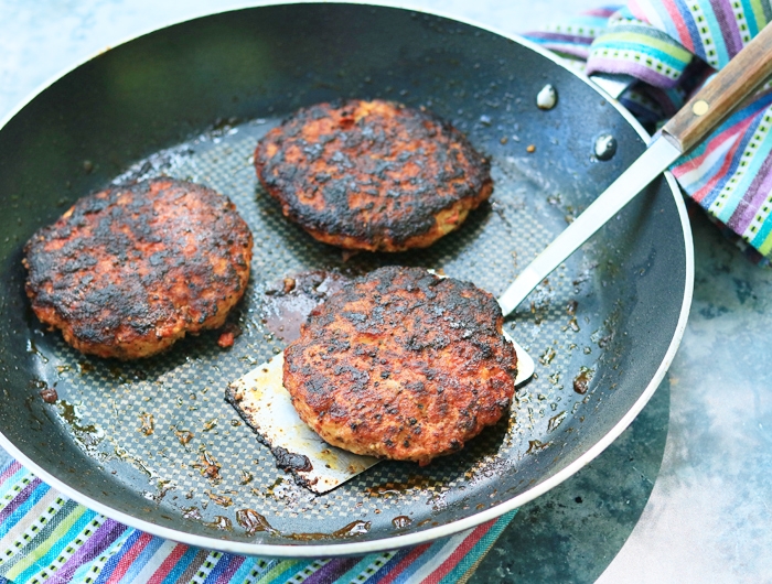 pan with three cooked chicken burger