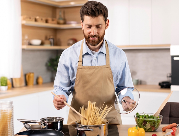 a man cooking pasta in a kitchen