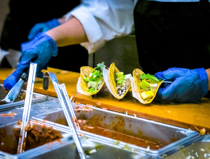 School cafeteria worker serving tacos to student