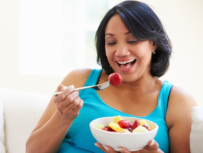 woman eating a bowl of cut fruit