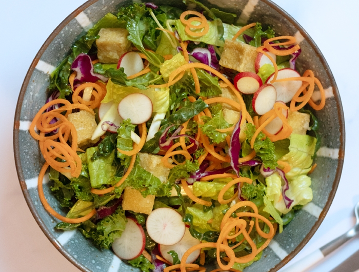 bowl of salad with greens and sliced vegetables