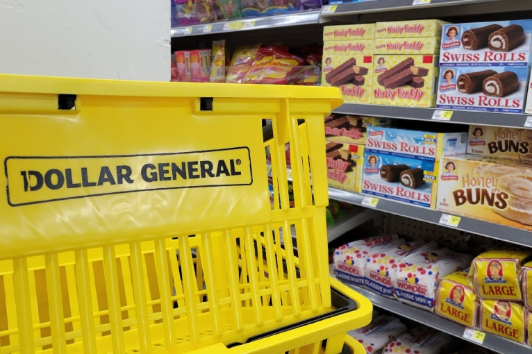 A Dollar General grocery basket placed near a store aisle with bread and pastries