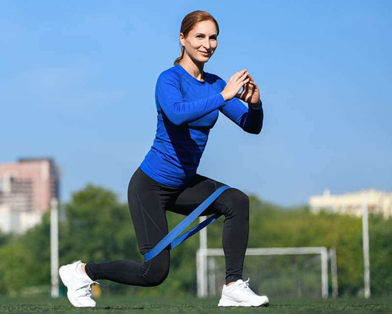 woman doing exercises with a resistance band outside