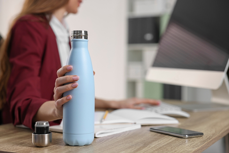 woman at a desk with a reusable water bottle