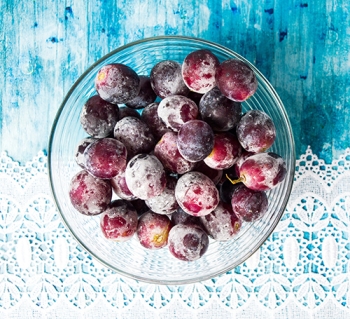 blow of frozen red grapes on blue background