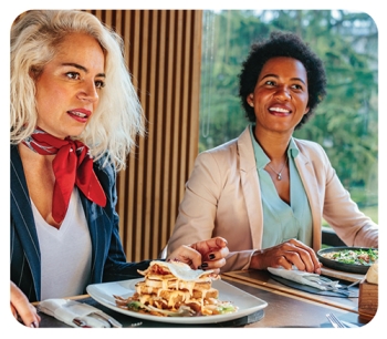 2 women sitting at a table with filled plates of food