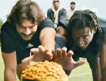 2 men reaching towards a pile of almonds in the foreground